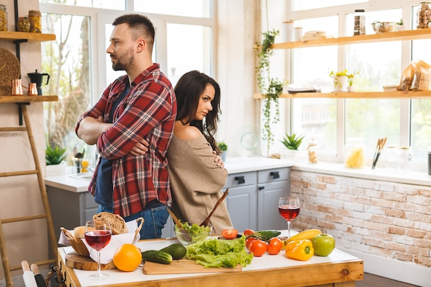 Pareja teniendo una pelea. El hombre y la mujer están regañando mientras está de pie en la cocina