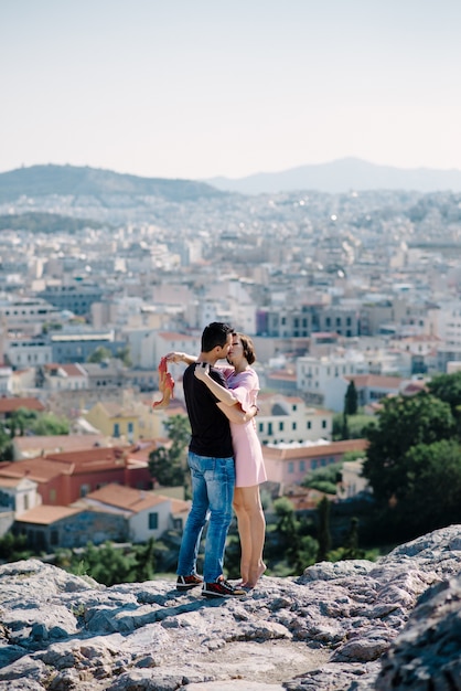 Pareja tiene una cita en la cima de la colina con vista panorámica de la ciudad besándose