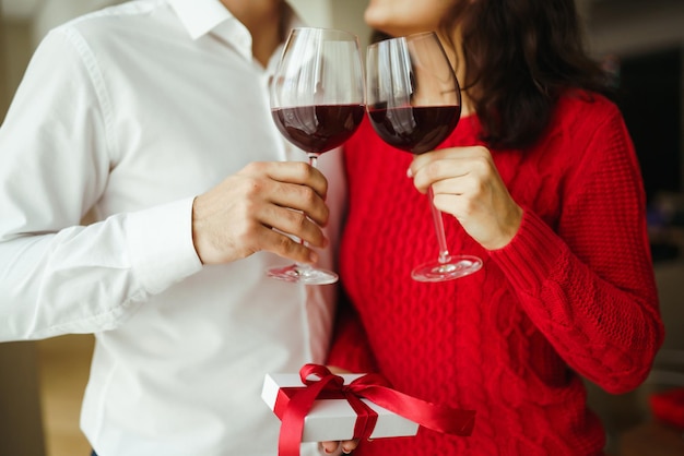 Pareja tintinea copas con vino tinto Los amantes se dan regalos Encantadora cena romántica