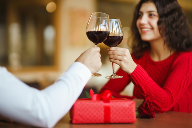 Pareja tintinea copas con vino tinto Los amantes se dan regalos Encantadora cena romántica