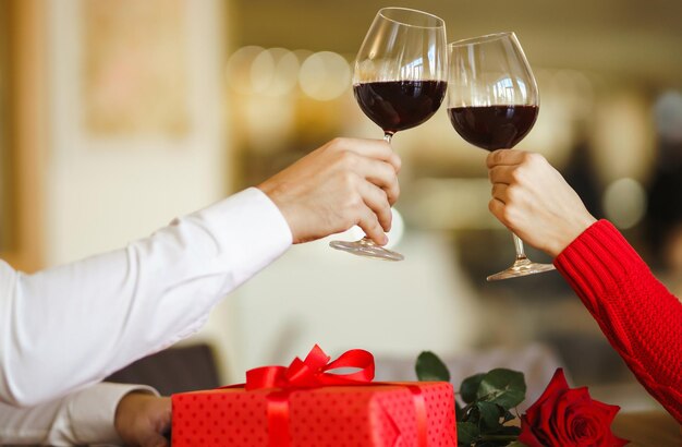 Pareja tintinea copas con vino tinto Los amantes se dan regalos Encantadora cena romántica