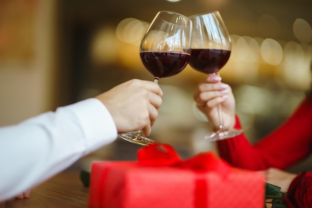 Pareja tintinea copas con vino tinto Los amantes se dan regalos Encantadora cena romántica