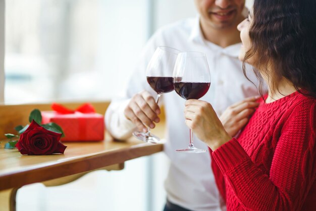 Pareja tintinea copas con vino tinto Romance en el restaurante para el concepto del Día de San Valentín