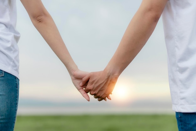 Pareja tomados de la mano en campo verde al atardecer