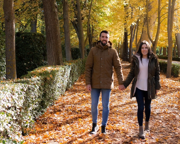 Pareja tomados de la mano mientras pasea en un día de otoño