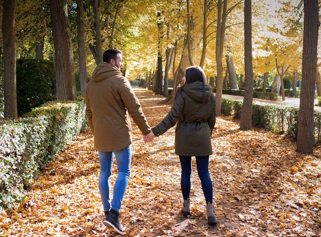 Pareja tomados de la mano mientras pasea en un día de otoño