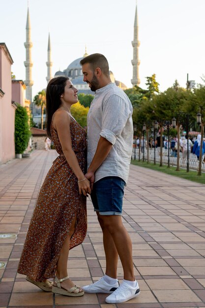 Pareja tomados de la mano y mirándose a los ojos en primer plano con la Mezquita Azul al fondo en Estambul, Turquía
