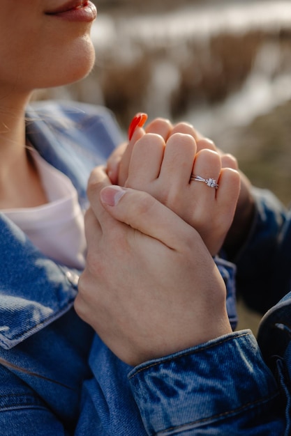 Una pareja tomados de la mano, la palabra amor en el anillo.