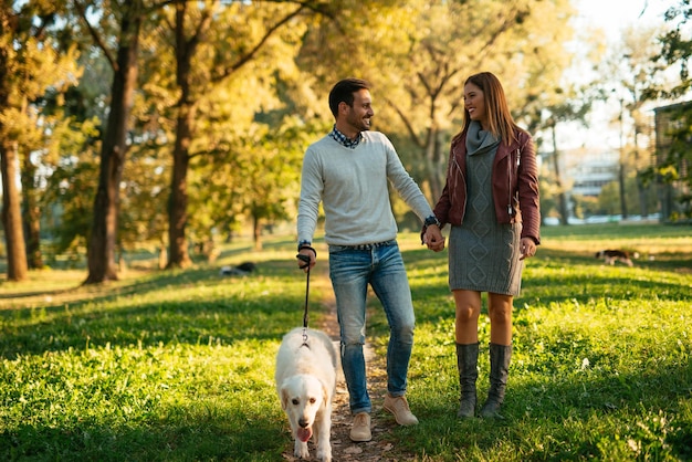 Pareja tomados de la mano y paseando al perro en el parque