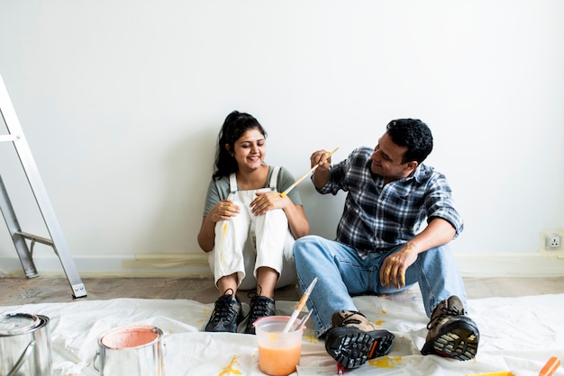 Foto pareja tomando un descanso de pintar las paredes