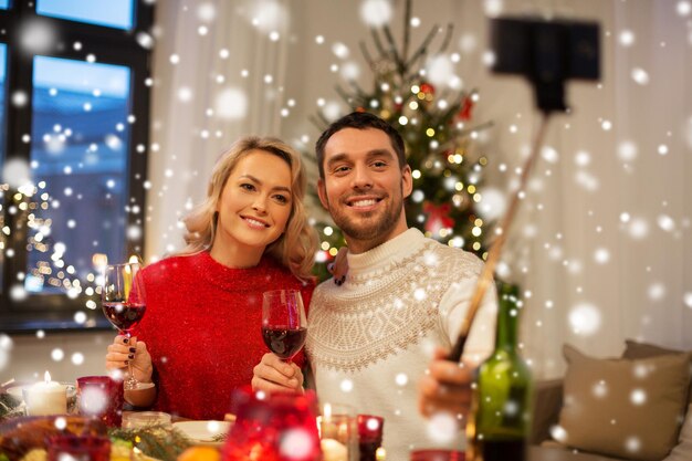 Foto una pareja tomando una foto con un palo de selfie en navidad