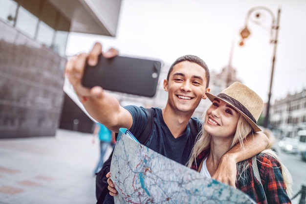 Pareja tomando selfie con mapa en la calle