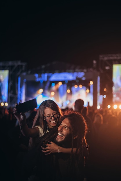 Pareja tomando selfie con un teléfono inteligente en un festival de música