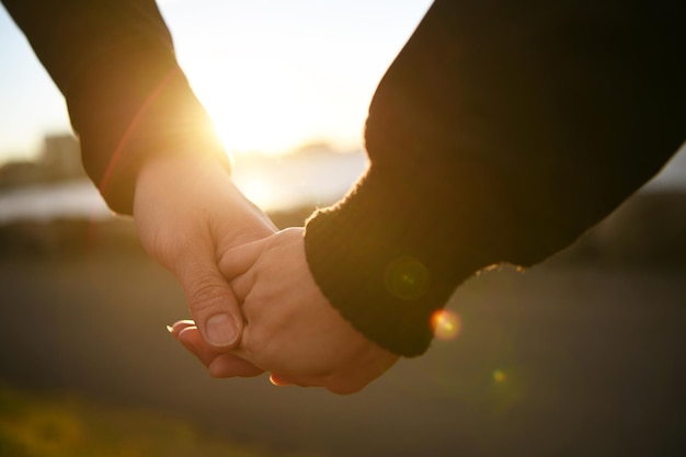 Una pareja tomándose de la mano durante la puesta del sol