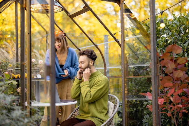 La pareja trabaja de forma remota en una computadora portátil en un invernadero en el patio trasero