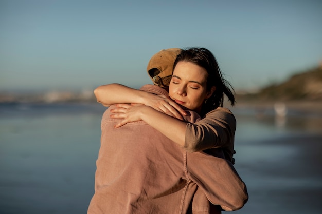 Pareja trans abrazándose en la playa al atardecer