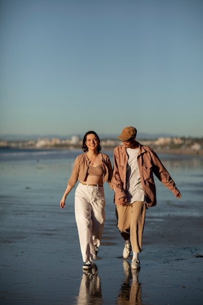 Foto pareja trans caminando por la playa al atardecer