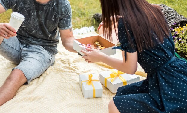 Una pareja se trata con los tradicionales postres franceses eclairs o profiteroles Una pareja joven haciendo un picnic en el día de verano