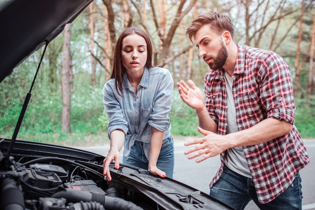 pareja tratando de arreglar el motor del auto