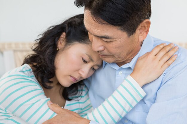 Pareja triste abrazando en casa