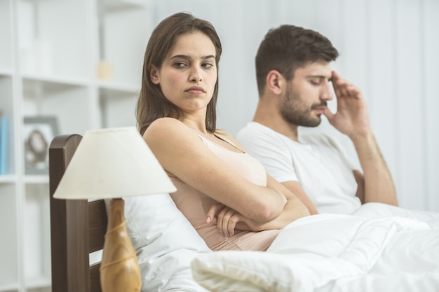 La pareja triste se sienta en la cama