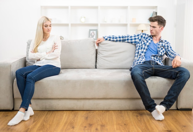 La pareja triste se sienta en el sofá