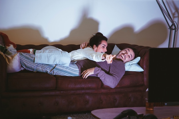 Foto pareja tumbada en el sofá y viendo una película