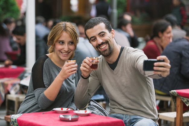 Pareja turca tomando Selfie mientras bebe Cay, té tradicional