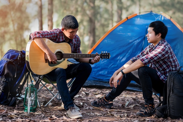 pareja turista jugando guitarra acústica tiempo de acampar