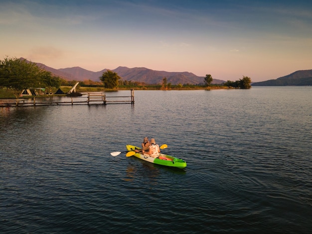 Pareja de turistas en canoa por el lago en el campo al atardecer