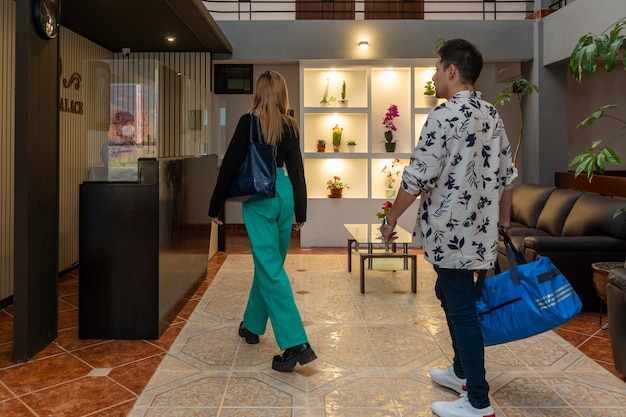 Pareja de turistas entrando en la recepción de un hotel de lujo, en una ciudad turística.