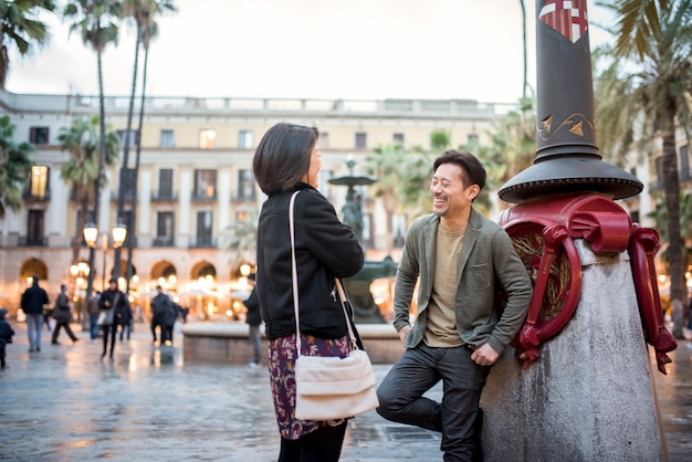 Pareja de turistas felices asiáticos hablando en una plaza