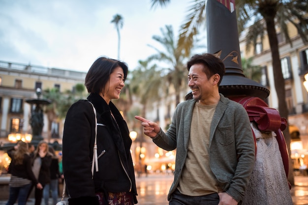 Pareja de turistas felices asiáticos hablando en una plaza