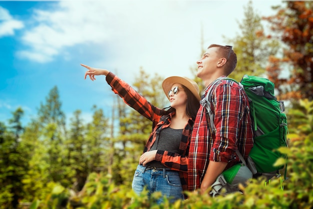 Pareja de turistas con mochilas viajando por el bosque. Senderismo en el bosque de verano. Caminata aventura de hombre y mujer joven.