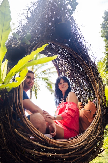 Una pareja de turistas sentados en un gran nido de pájaro en un árbol en la isla de Bali