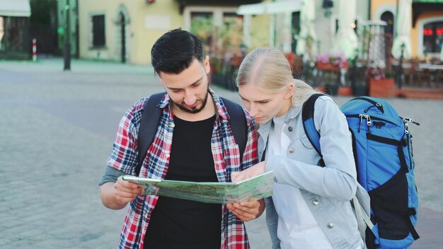 Pareja de turistas sosteniendo un mapa para encontrar un nuevo lugar interesante para hacer turismo