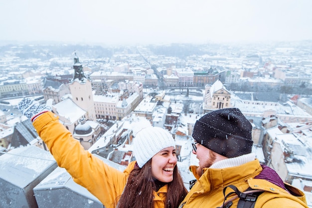 Foto pareja de turistas tomando selfie con hermosa vista de la ciudad en invierno en el fondo