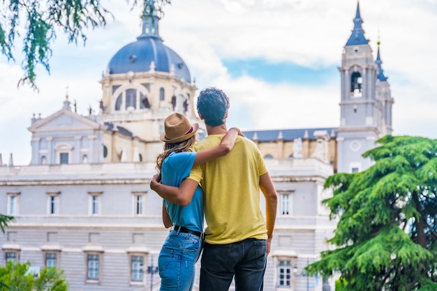 Pareja de turistas visitando la ciudad de Madrid en vacaciones de verano Concepto de vacaciones para viajeros con la espalda mirando a la Almudena