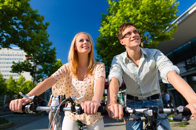 Pareja urbana montando bicicleta en el tiempo libre en la ciudad