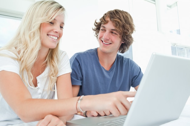 Una pareja usa una computadora portátil con un hombre mirando a la mujer