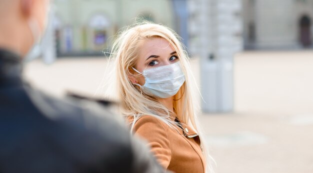 La pareja usa una máscara médica que camina en la calle de la ciudad durante la difusión de noticias sobre la epidemia de coronavirus.