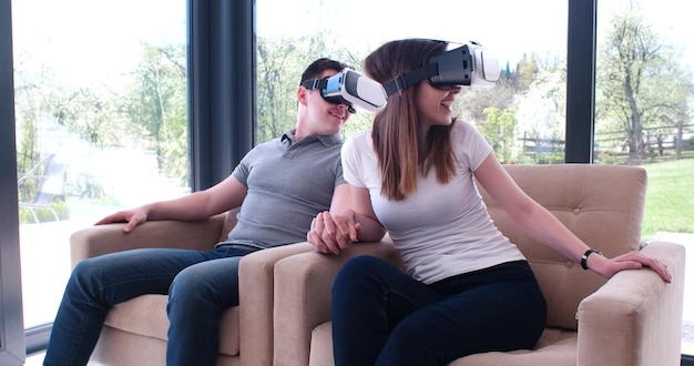 Pareja usando auriculares de realidad virtual en la sala de estar en casa personas jugando con tecnología de nuevas tendencias