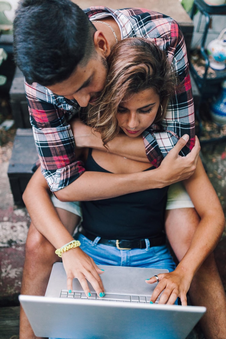 Foto una pareja usando una computadora portátil mientras están sentados en el patio trasero