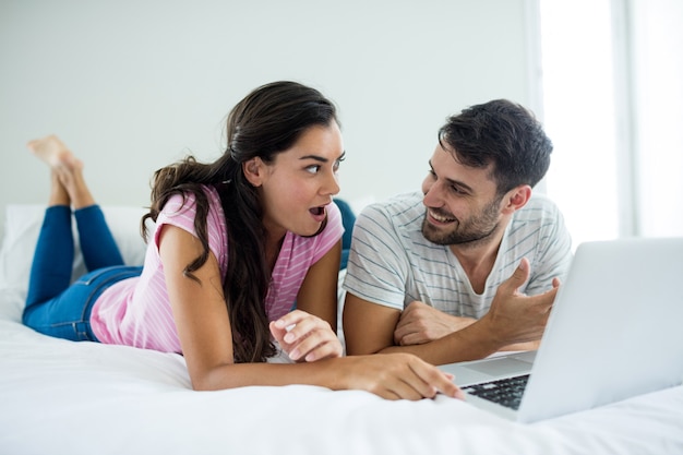 Pareja usando laptop en el dormitorio en casa