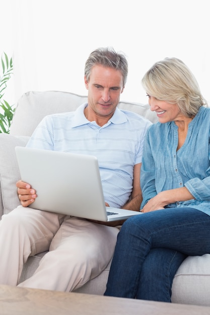 Pareja usando laptop juntos en el sofá