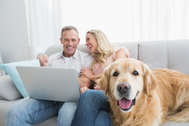 Pareja usando laptop y pasar tiempo con su perro