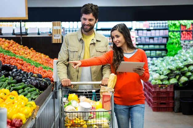 Pareja usando tableta digital mientras compras