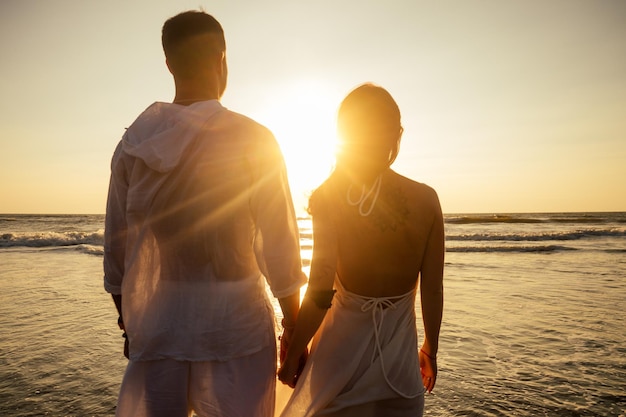 Pareja de vacaciones caminando en la playa juntos enamorados al atardecer goa