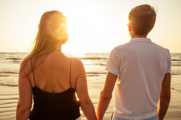 Pareja de vacaciones caminando en la playa juntos enamorados al atardecer goa