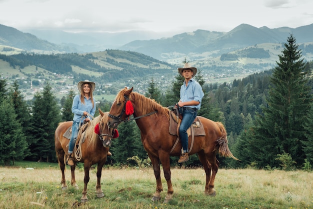 Pareja de vaqueros a caballo en las montañas